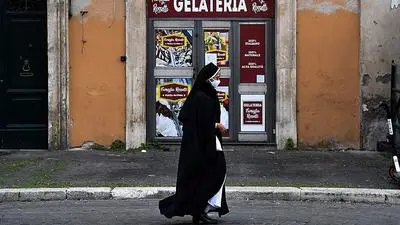 A nun walks past a closed ice-cream parlor on February 17, 2021 in central Rome. - Italy on February 12 extended a domestic travel ban and tightened restrictions in four regions amid rising concern about the spread of more infectious coronavirus variants. (Photo by Tiziana FABI / AFP)