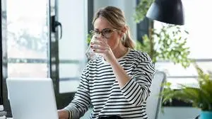 Shot of beautiful mature business woman working with a laptop while drinking glass of water on a desk in the office at home.