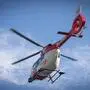 Man sieht einen rot-weißen Rettungshubschrauber in der Luft