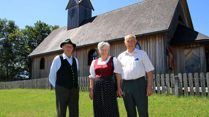 Franz Zwanzger, Elisabeth Dohr und Johann Gruber vor der Kirche aus Holz
