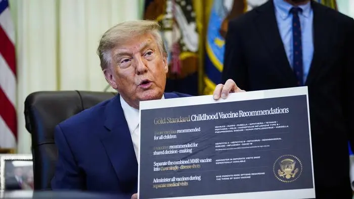 Donald Trump hält ein Schild mit den „Goldstandard Kinderimpfempfehlungen“