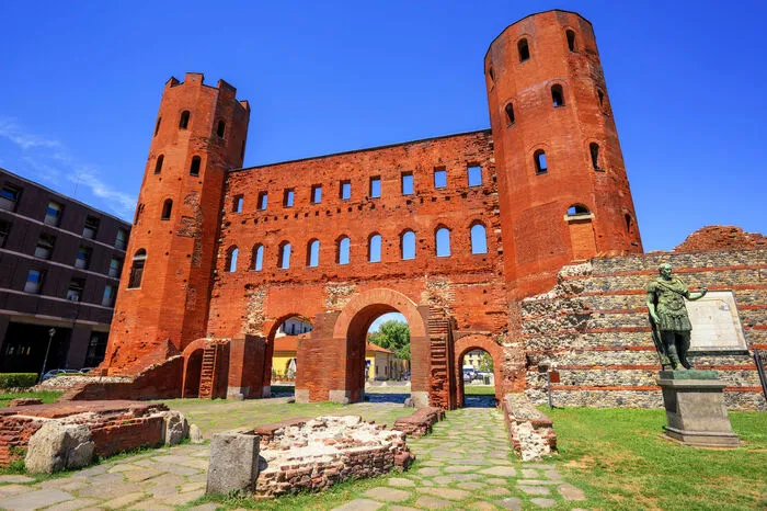 Die Porte Palatine (Bild) ist das einzige erhaltene Stadttor des römischen Turins. Einen kulinarischen Zwischenstopp sollte man auf der Porta Palazzo einlegen, wo sich einer der größten Freiluftmärkte Europas befindet.