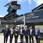 Mehrere Menschen stehen nebeneinander und lachen in die Kamera, dahinter die Solaranlage 
