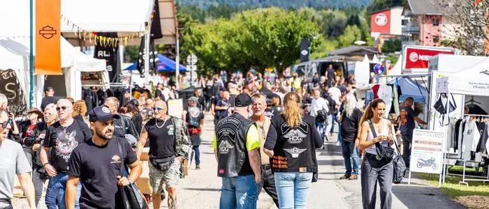Mehrere Menschen spazieren auf einem Festgelände
