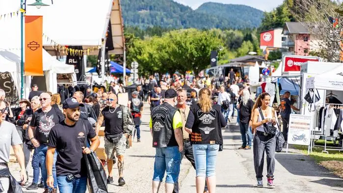 Mehrere Menschen spazieren auf einem Festgelände