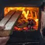Man putting log to wood burning stove. Close up