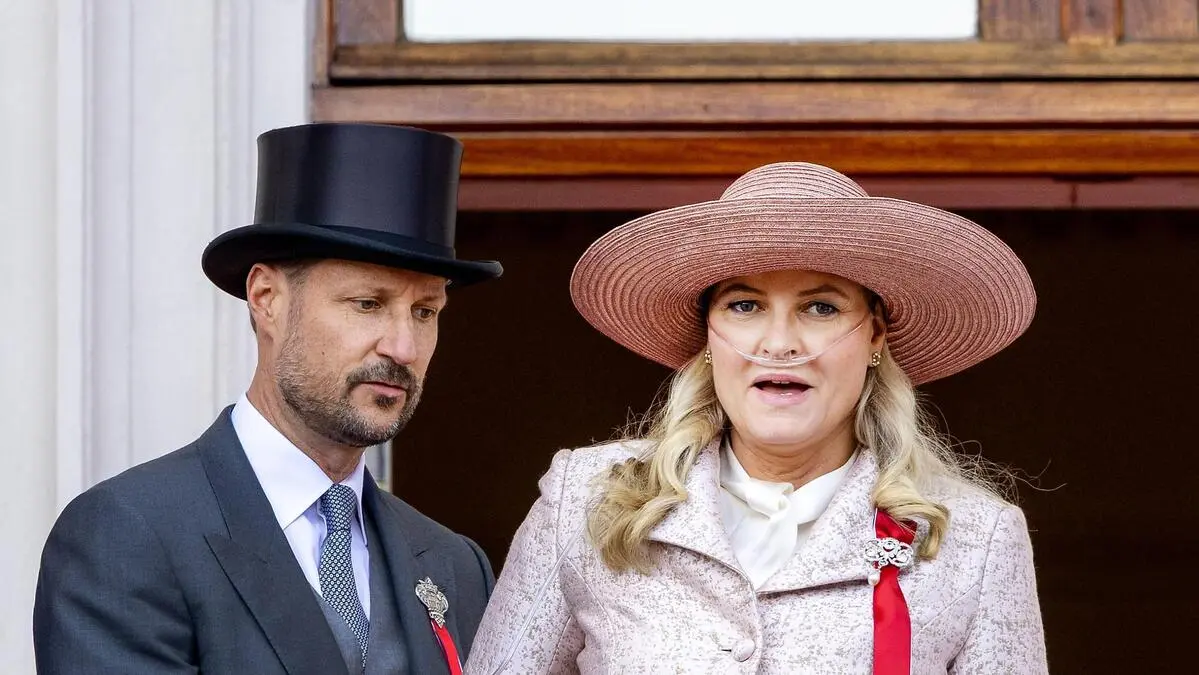 Kronprinz Haakon und Kronprinzessin Mette-Marit stehen auf einem Balkon. An der Brüstung sind Pflanzen und kleine norwegische Flaggen angebracht