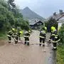 Sechs Feuerwehrleute arbeiten an einer überfluteten Straße