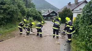 Sechs Feuerwehrleute arbeiten an einer überfluteten Straße