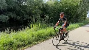 Ein Mann fährt auf seinem Rennrad, im Hintergrund grüne Sträucher