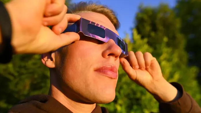 Das Bild zeigt einen Mann, der sich eine Sonnenfinsternisbrille vor die Augen hält