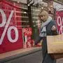 FILE - A woman walks with purchases past a store in Berlin, Germany, Friday, April 1, 2022. The European economy scraped out meager growth of 0.1% in the first three months of the year, barely gaining momentum after dodging a winter recession as challenges persist from inflation that corrodes people’s willingness to spend. (AP Photo/Pavel Golovkin, File)