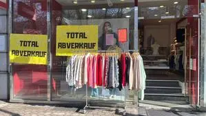 Ein Geschäft von außen, auf dem Schaufenster kleben Plakate, die auf den Totalabverkauf hinweisen