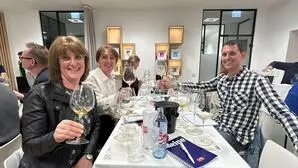 Zwei Frauen und ein Mann stoßen mit Wein an