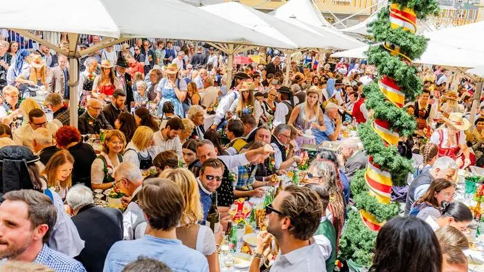 Blick auf einen vollen Platz mit Bierbänken. Sehr viele Menschen sitzen und stehen und haben Tracht an