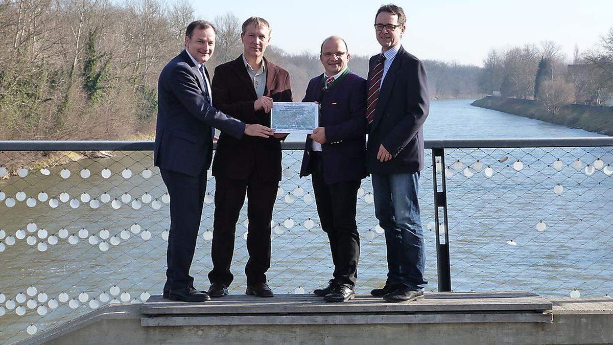 Bezirkshauptmann Alexander Majcan, Bürgermeister Stanislav Rojko, der Landtagsabgeordnete Anton Gangl und Bürgermeister Josef Sommer vor jenem Bereich der Mur, über den die Eisenbahnbrücke führen wird