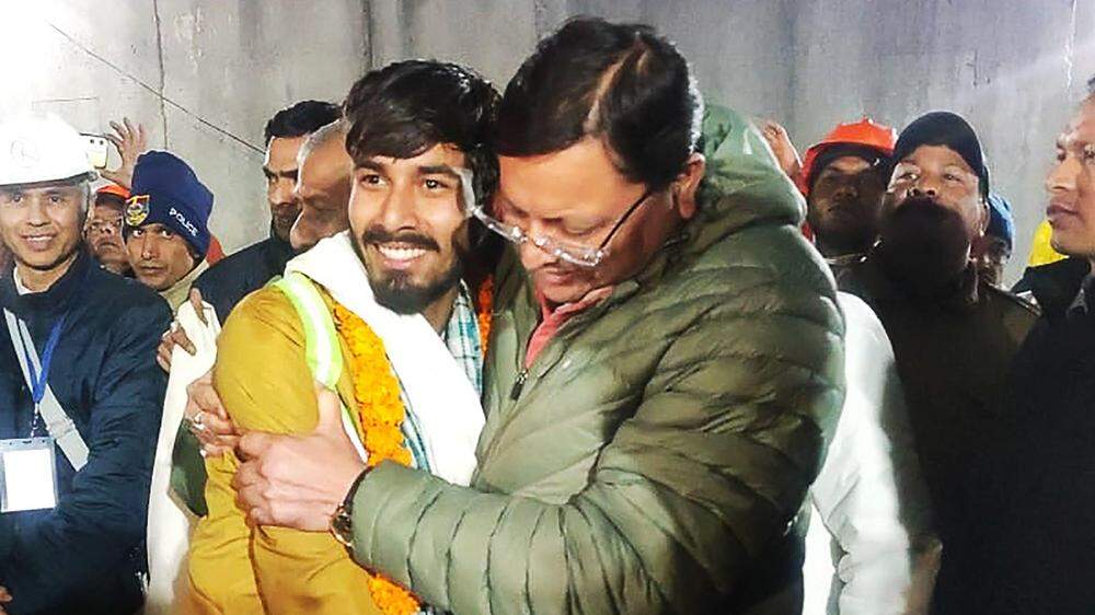 Regierungschef des Bundesstaates Uttarakhand, Pushkar Singh Dhami (r), umarmt einen geretteten Bauarbeiter. | Regierungschef des Bundesstaates Uttarakhand, Pushkar Singh Dhami (r), umarmt einen geretteten Bauarbeiter. 