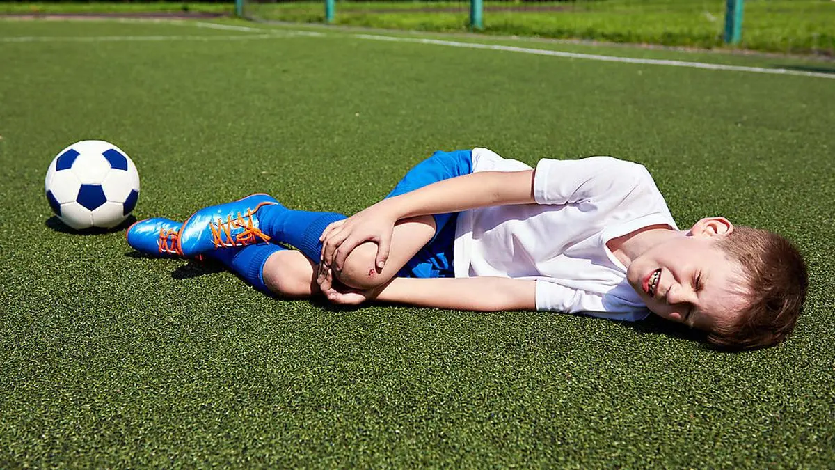 Injury of the knee in the boy football soccer player on grass