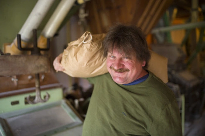 Wiege trägt einen 25 Kilogramm schweren Getreidesack.