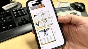 Eine Hand hält ein Handy und zeigt einen WhatsApp-Verlauf mit verbotenen Symbolen aus der rechtsextremen Szene | In Österreich gibt es viele verbotene und strafrechtlich relevante Symbole – nicht nur aus der rechtsextremen Szene