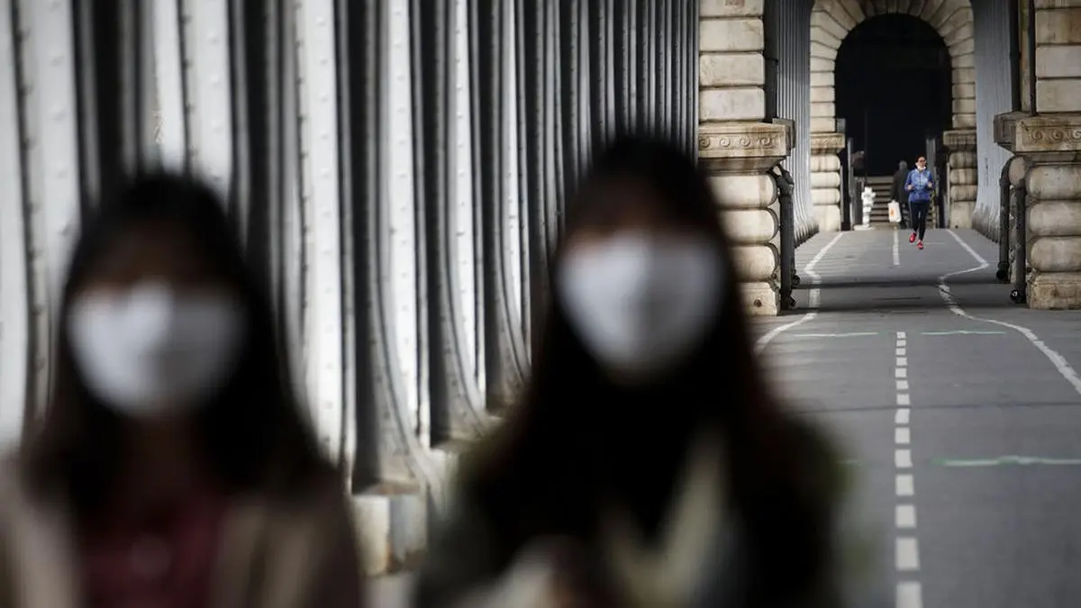 Tourists wearing masks walk on the Bir-Hakeim bridge in Paris, Wednesday, March 18, 2020. French President Emmanuel Macron said that for 15 days people will be allowed to leave the place they live only for necessary activities such as shopping for food, going to work or taking a walk. For most people, the new coronavirus causes only mild or moderate symptoms. For some it can cause more severe illness, especially in older adults and people with existing health problems. (AP Photo/Christophe Ena)