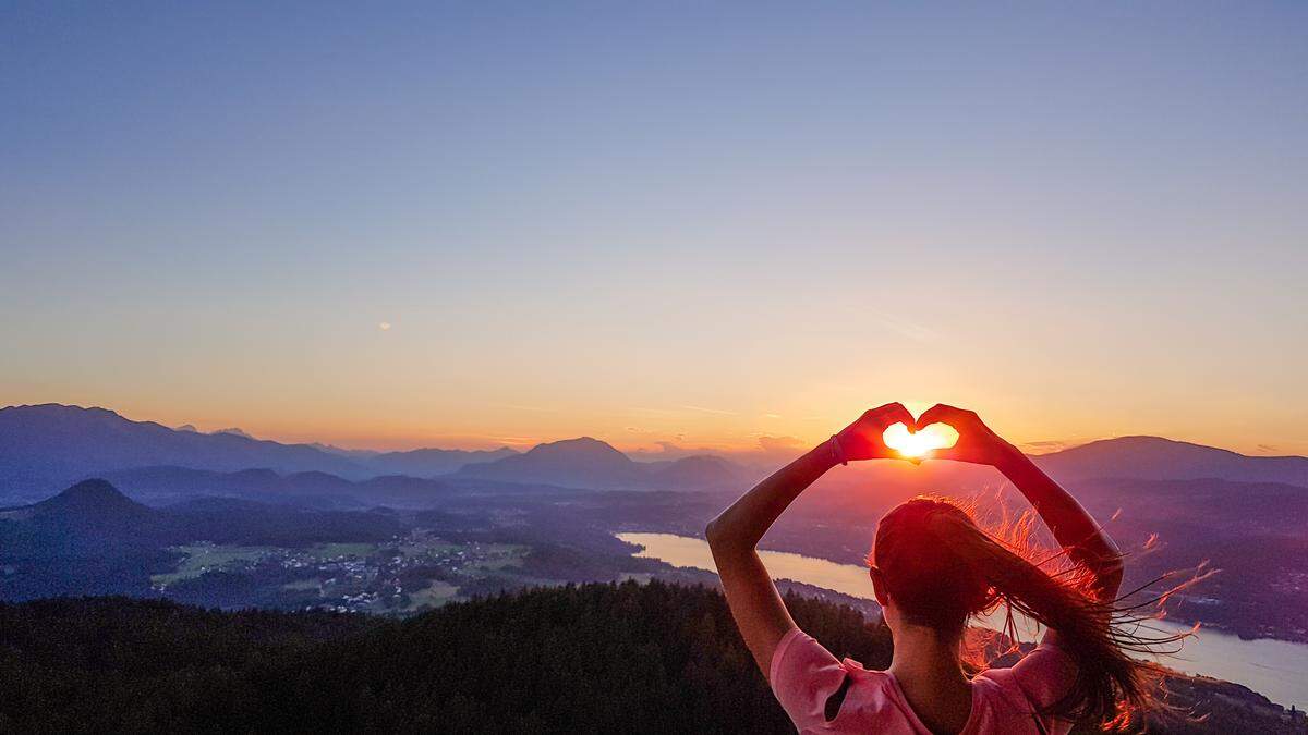 Austria - Girl forming a heart with her hands, holding sun in the frame