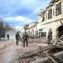 TOPSHOT - Croatian soldiers stand next wreckage and damaged buildings in Petrinja, some 50kms from Zagreb, after the town was hit by an earthquake of the magnitude of 6,4 on December 29, 2020. - The tremor, one of the strongest to rock Croatia in recent years, collapsed rooftops in Petrinja, home to some 20,000 people, and left the streets strewn with bricks and other debris. Rescue workers and the army were deployed to search for trapped residents, as a girl was reported dead. (Photo by Damir SENCAR / AFP)