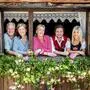 Eine Familie blickt lächelnd durch ein mit Blumen dekoriertes Fenster
