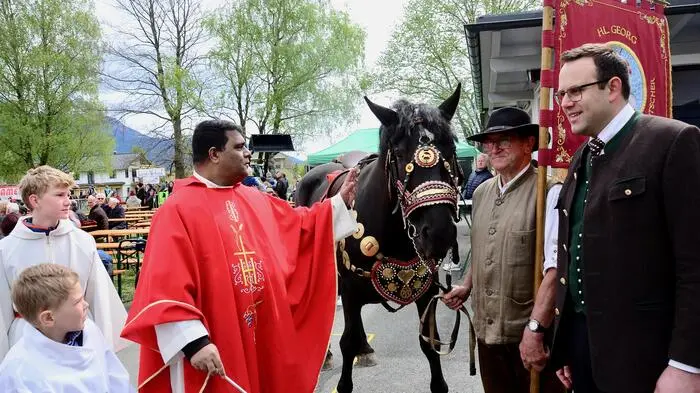 Pferdesegnung durch Pfarrer Sibu Vargheese, assistiert von Ministranten, mit Fahnenträger Hans Furtner und Mitorganisator Stephan Dollinger