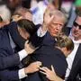Republican presidential candidate former President Donald Trump is helped off the stage by U.S. Secret Service agents at a campaign event in Butler, Pa., on Saturday, July 13, 2024. (AP Photo/Gene J. Puskar)