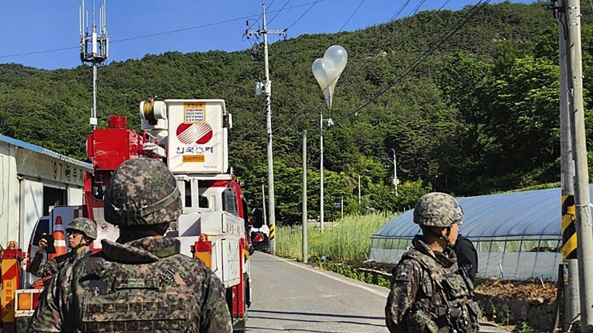 Ballons mit vermutlich von Nordkorea verschicktem Mist hängen an Stromkabeln, während südkoreanische Soldaten Wache stehen.