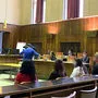 Sieben junge Männer und Frauen stehen vor Gerich