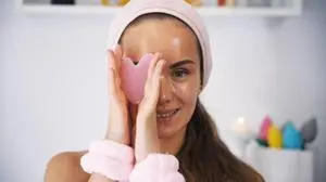 Eine Beauty-Bloggerin hält Gua Sha in der Nähe ihres Gesichts und bedeckt damit ein Auge A beauty blogger girl holds a Gua Sha tool near her face, playfully covering one eye with it, highlighting her skincare routine in a stylish and engaging manner LicenseRF ,model released, Symbolfoto Copyright: xZoonar.com/AndreiixMoiseix 23935055 ,model released, Symbolfoto ,property released