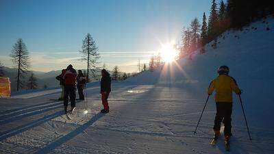 Ski fahren schon frühmorgens, wenn sich die Sonne über den Berghang schiebt