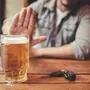Do not drink and drive! Cropped image of man showing stop gesture and refusing to drink beer. Car keys lying near