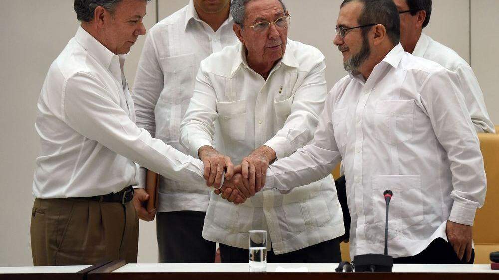 Die Aufnahme vom 23. September 2015 zeigt den damaligen kolumbianischen Präsidenten Juan Manuel Santos (links) und den Chef der Farc-Guerilla Rodrigo Londono  alias Timochenko (rechts), während der kubanische Präsident Raul Castro (Mitte) ihre Hände bei einem Treffen in Havanna zusammenführt
