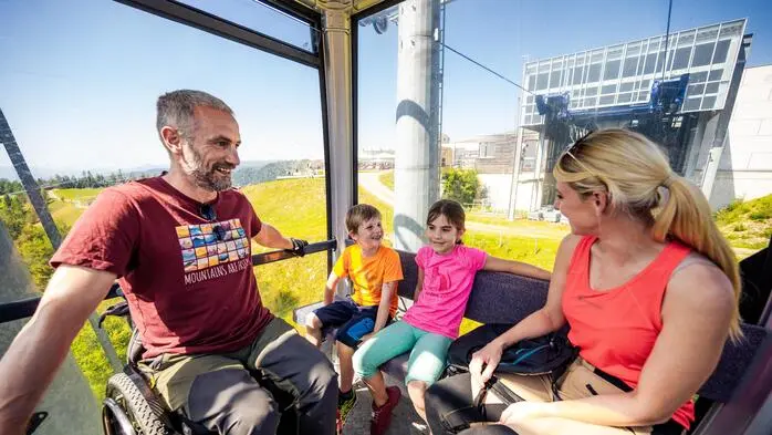 Eine Familie sitzt in einer Bergbahn im Sommer
