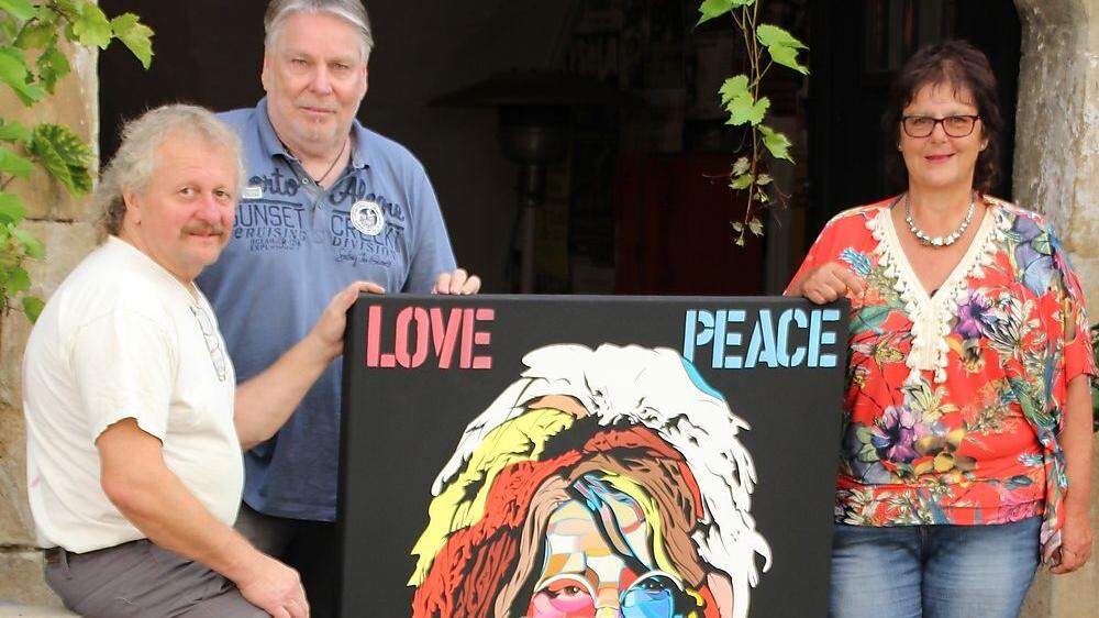 Andres Klimbacher, Roman Kobald und Burgfrau Astrid Pranger mit einem Bild, das Janis Joplin zeigt. Die Drei holen das richtige Woodstock in die Herzogburg
