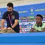 A team official grabs a cat to get it down from the conference table as Brazil's forward #20 Vinicius Junior speaks during a press conference at the Al Arabi SC Stadium in Doha on December 7, 2022, during the Qatar 2022 World Cup football tournament. - Brazil and Croatia will meet in one of the Qatar 2022 World Cup quarter-finals on December 9. (Photo by NELSON ALMEIDA / AFP)