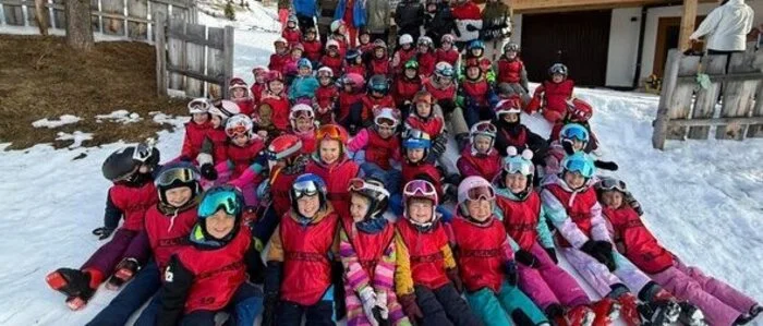 Die Kinder aus den Skiferienkursen sitzen im Schnee