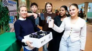 Schülerinnen und Schüler, die ihre Smartphones in eine Box stecken 