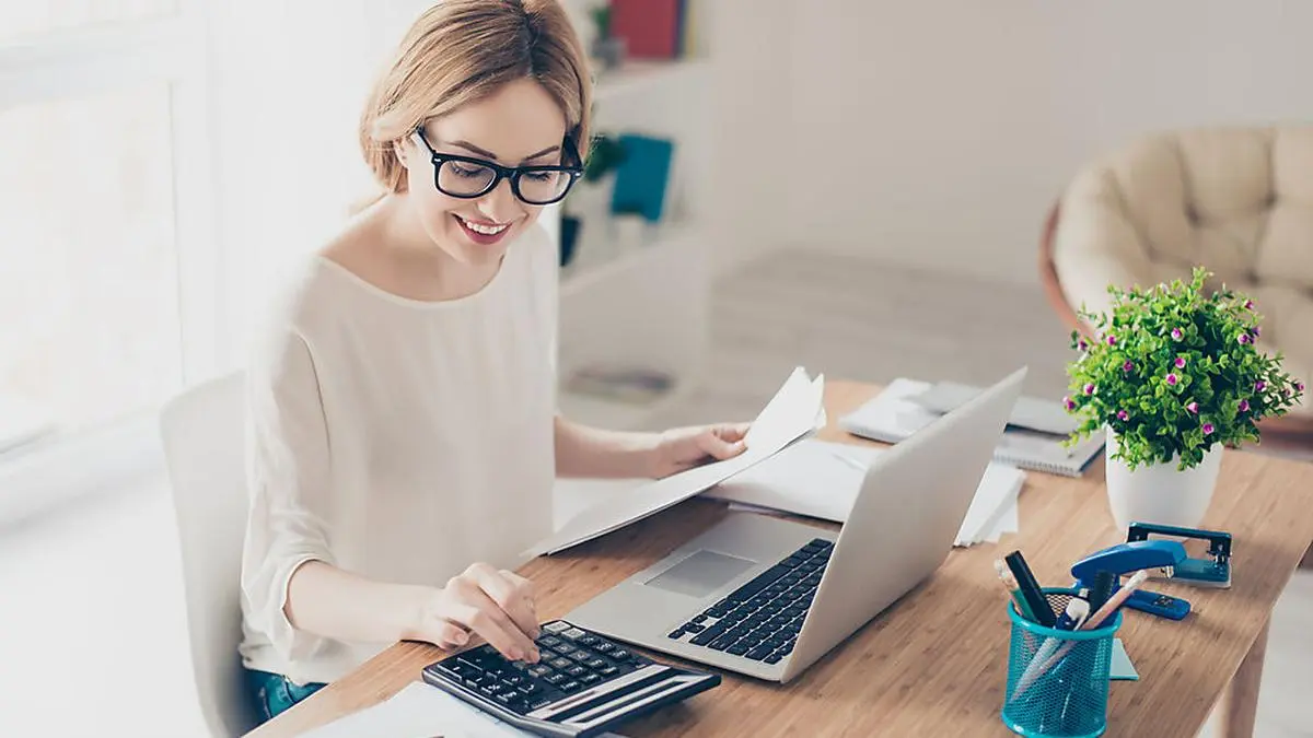 Happy cute  pretty accountant working with computer and calculator