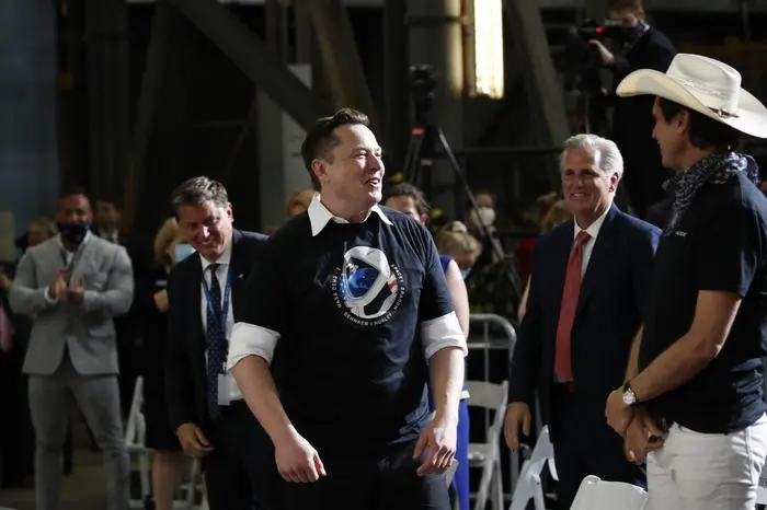 Tesla and SpaceX Chief Executive Officer Elon Musk stands as his brother Kimbal Musk, right, and House Minority Leader Kevin McCarthy of Calif., look on during an event at the Vehicle Assembly Building on Saturday, May 23, 2020, after a SpaceX flight at NASA's Kennedy Space Center in Cape Canaveral, Fla. A rocket ship designed and built by SpaceX lifted off on Saturday with two Americans on a history-making flight to the International Space Station. (AP Photo/Alex Brandon)