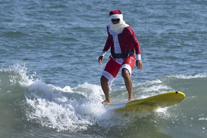 Ein Mann im Weihnachtsmannkostüm beim Surfen in Cocoa Beach, Florida.