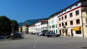 Town center square in Vipava in Littoral region of Slovenia with cars parked in the street and buidling lit by sunlight
