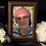 Eine Foto von einer Frau in einem Bilderrahmen, daneben liegen weiße Blumen