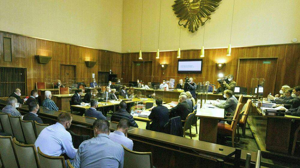 Die Angeklagten (links) und ihre Anwälte (rechts) beim Prozessauftakt gegen 24 Angeklagte unter anderem wegen gewerbsmäßigen Bierdiebstahls am Montag am Straflandesgericht in Graz