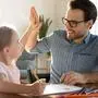 Head shot happy little child girl giving high five to affectionate loving father, finishing drawing picture together at home. Smiling young dad celebrating good work done with cute small daughter.
