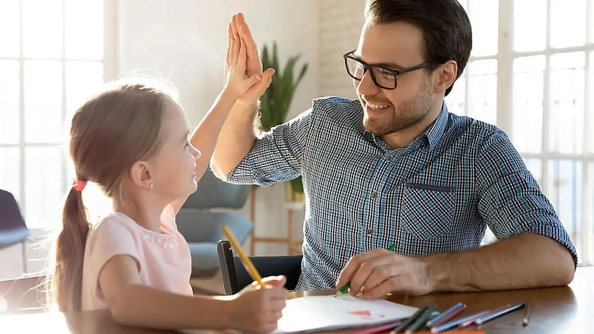 Head shot happy little child girl giving high five to affectionate loving father, finishing drawing picture together at home. Smiling young dad celebrating good work done with cute small daughter.