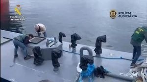 Drei Männer stehen auf dem Deck eines Bootes. In der oberen Bildhälfte ist ruhiges Wasser zu sehen. Die Männer wirken beschäftigt, ein Mann fotografiert in eine Luke.  | Alles musste blitzschnell gehen, weil die Besatzungen solcher Drogen-Tauchboote üblicherweise versuchen, das Schiff zu versenken, um Beweise zu vernichten. Die Polizeioperation gelang.